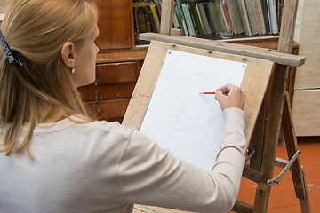 Image showing A young girl paints on an easel in the studio of the artist