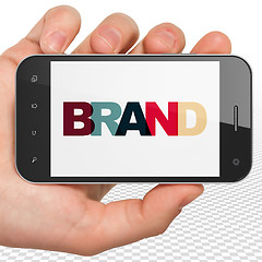 Image showing Marketing concept: Hand Holding Smartphone with Brand on  display