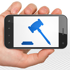 Image showing Law concept: Hand Holding Smartphone with Gavel on display