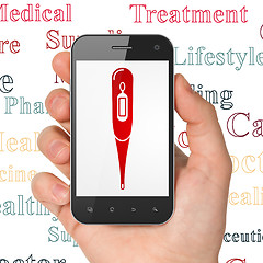 Image showing Medicine concept: Hand Holding Smartphone with Thermometer on display