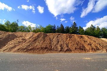 Image showing storage of wooden bio fuel against blue sky