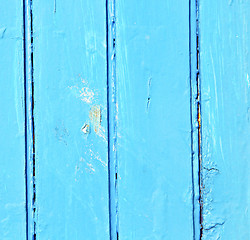 Image showing stripped paint in the blue wood door and rusty nail