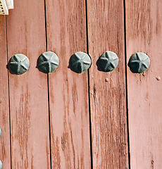 Image showing nail dirty stripped paint in the brown wood door and rusty yello