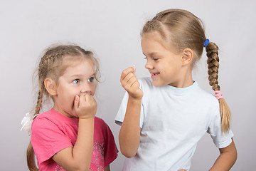 Image showing Four-year girl with horror looks at the lost tooth in his hand a six-year girl