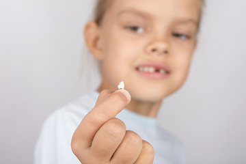 Image showing Six year old girl holding a fallen tooth and smiling looking at him