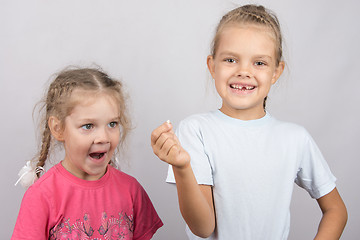 Image showing Four-year girl with surprise stares at the lost tooth in his hand a six-year girl