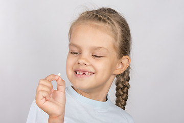 Image showing Six year old girl with a smile looking at the fallen baby tooth