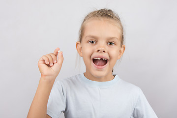 Image showing Girl holds the tooth in his hand and his mouth open showing a hole between the teeth