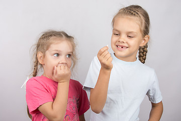 Image showing Four-year girl with the fear of looking at the lost tooth in his hand a six-year girl