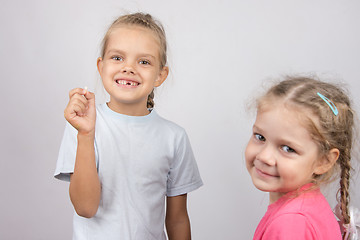 Image showing Girl holding a fallen front tooth, standing next to another girl