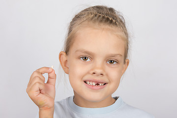 Image showing Portrait of a girl with a fallen tooth in his hand