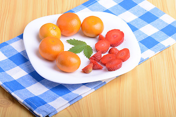 Image showing A slice of red strawberry on white plate with mandarin and strawberry slices