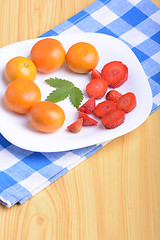 Image showing A slice of red strawberry on white plate with mandarin and strawberry slices