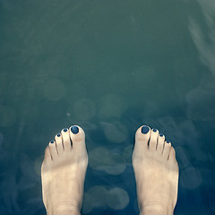 Image showing Bare feet over the water