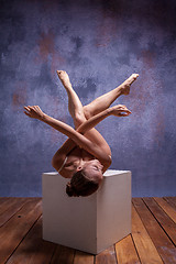 Image showing Young beautiful dancer in beige swimwear posing on white cube