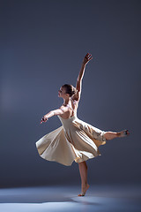 Image showing Young beautiful dancer in beige dress dancing on gray background