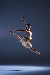 Image showing Young beautiful dancer in beige dress jumping on gray background