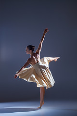 Image showing Young beautiful dancer in beige dress dancing on gray background