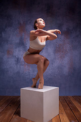 Image showing Young beautiful dancer in beige swimwear posing on white cube