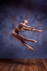 Image showing Young beautiful dancer in beige swimwear dancing on lilac background