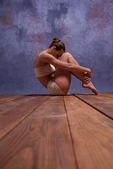 Image showing Young beautiful dancer in beige swimwear dancing on lilac background