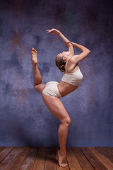 Image showing Young beautiful dancer in beige swimwear dancing on lilac background