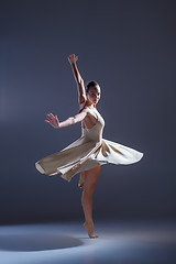 Image showing Young beautiful dancer in beige dress dancing on gray background