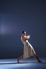 Image showing Young beautiful dancer in beige dress dancing on gray background