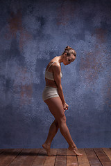 Image showing Young beautiful dancer in beige swimwear dancing on lilac background