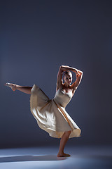 Image showing Young beautiful dancer in beige dress dancing on gray background