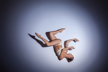 Image showing Young beautiful dancer in beige swimwear dancing on lilac background