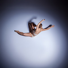 Image showing Young beautiful dancer in beige swimwear dancing on lilac background