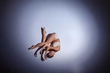 Image showing Young beautiful dancer in beige swimwear dancing on lilac background