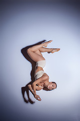 Image showing Young beautiful dancer in beige swimwear dancing on lilac background