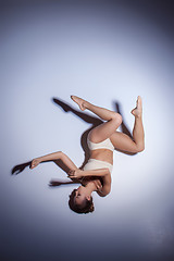 Image showing Young beautiful dancer in beige swimwear dancing on lilac background