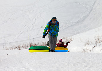 Image showing Father and daughter with snow tube