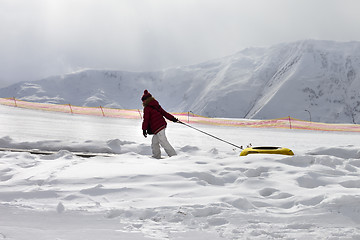 Image showing Girl with snow tube at sun gray day