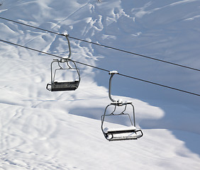 Image showing Two chair-lift with snowdrift and off-piste slope in sun morning