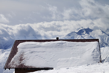 Image showing Snowy roof and mountains in clouds