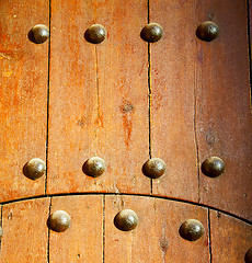 Image showing nail dirty stripped paint in the brown wood door and rusty yello