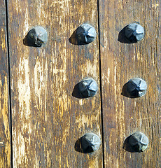 Image showing nail dirty stripped paint in the brown wood door and rusty yello