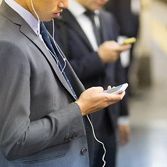 Image showing Businessmen using their cell phones on subway.