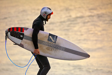 Image showing Surfer wearing gath surf helmet and wetsuit at sunrise