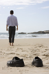 Image showing Manager walking barefoot on the beach