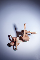 Image showing Young beautiful dancer in beige swimwear dancing on lilac background