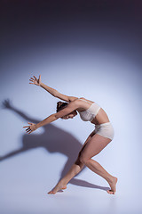 Image showing Young beautiful dancer in beige swimwear dancing on lilac background