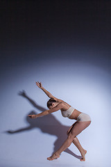 Image showing Young beautiful dancer in beige swimwear dancing on lilac background