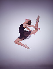 Image showing The silhouette of young ballet dancer jumping on a lilac  background.