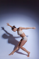 Image showing Young beautiful dancer in beige swimwear dancing on lilac background