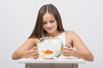 Image showing Pretty girl examines a goldfish in an aquarium